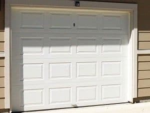 A white garage door on a home with beige siding.