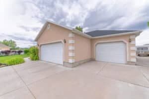 Two white clipped corner garage doors on a light pink house with a concrete driveway