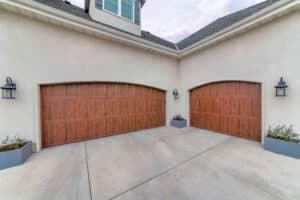 Decorated three-car garage exterior with wall lamps and two wooden doors