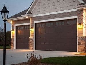 A house with a double- and single-garage door has a mixture of stone and vinyl siding.