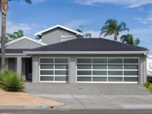 Grey home with three-car garage. Garage doors feature opaque glass and grids for a modern look