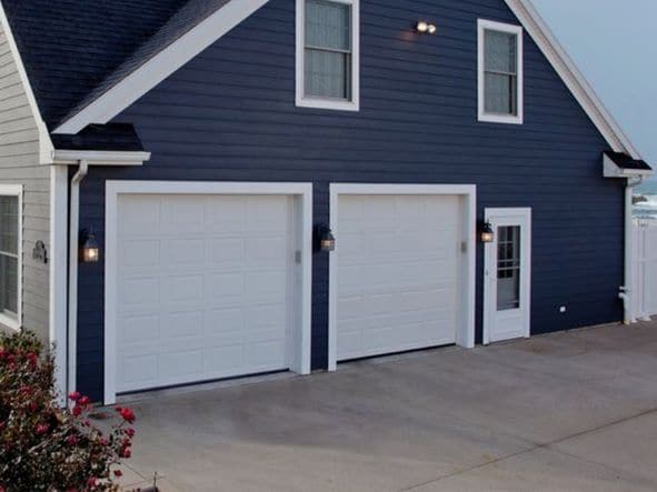 Dark blue home with two white garage doors
